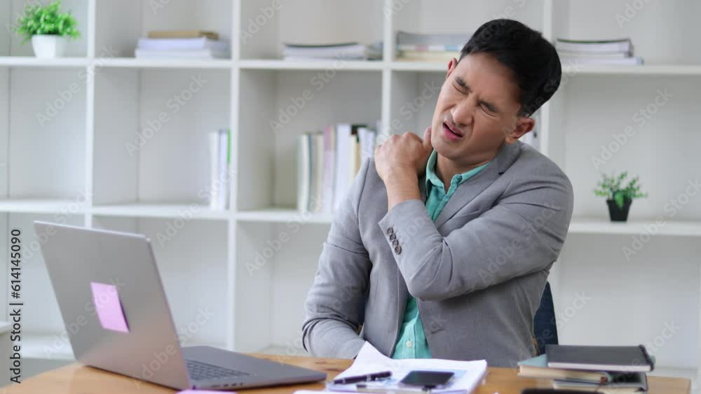 A sore businessman stretching to relax after working in the office. A sore businessman stretching to relax after working in the office.