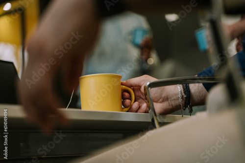 A close up photo of a man holding a yellow cup of coffee
