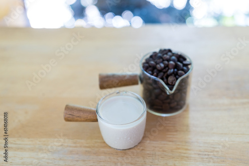 Coffee grains in mini glass cup and fresh milk in cup. Preparing fresh coffee at cafe