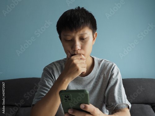 Asian man looking at smartphone screen, stressed and worried face, receive notification via email, message, investment that does not go as expected