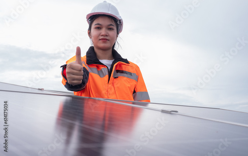 Beautiful Asian female engineer giving thumbs up after inspecting solar power station. Clean energy.