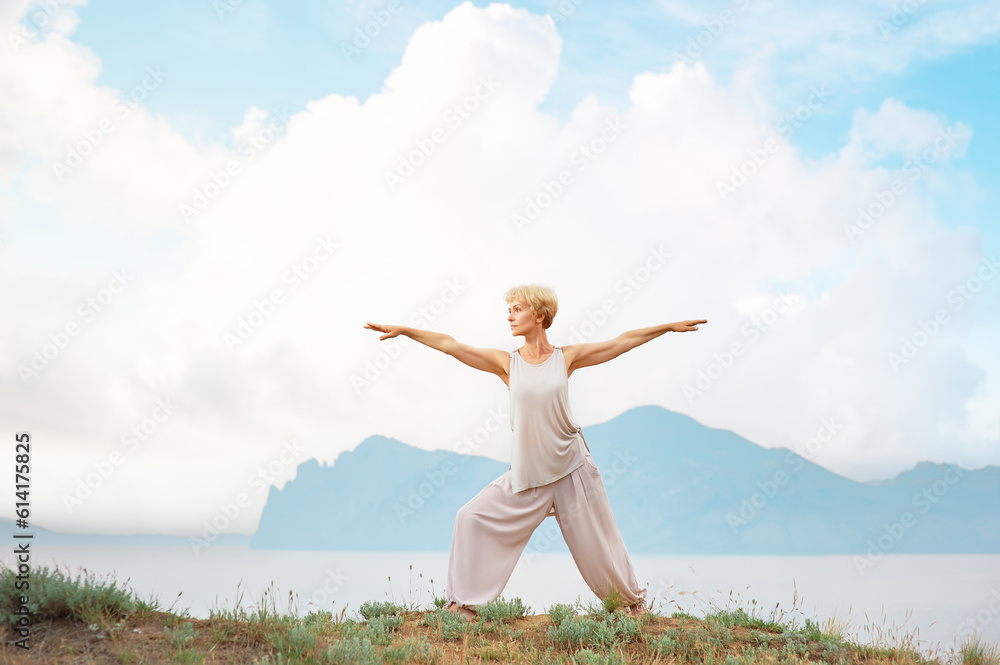 Senior woman doing yoga exercises with mountain on the background Senior woman doing yoga exercises with mountain on the background