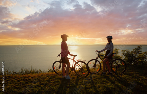 Two women with bicycles on the sea or lake shore