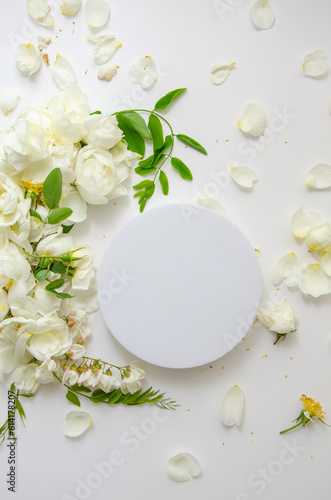 Delicate composition of white roses and petals with acacia flowers and round podium on white background. Wedding concept. Invitation card. Organic spa cosmetic presentation