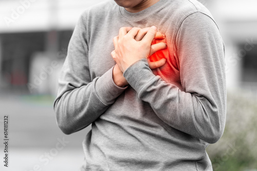 Man covering his heart painfully outdoors, concept of sudden heart attack.  photo