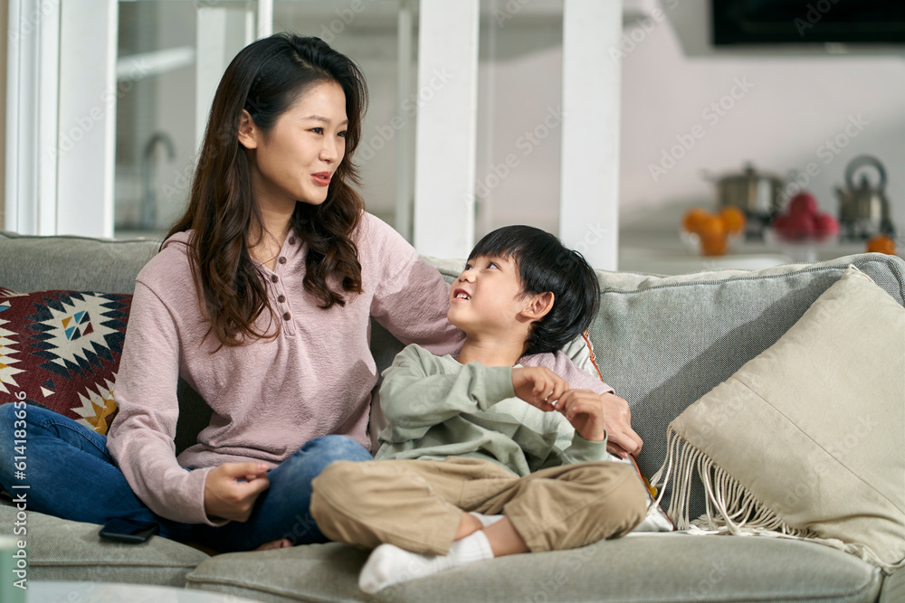 happy asian mother and son sitting chatting on family couch at home happy asian mother and son sitting chatting on family couch at home