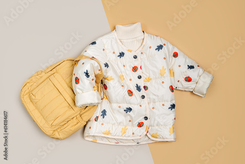 Stylish children's autumn warm jacket with yellow backpack. Fashion kids outfit for for spring, autumn or winter. Flat lay, top view