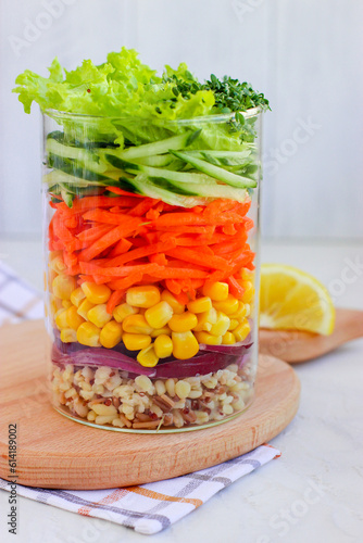 Healthy vegan salad with bulgur and vegetables in mason jar on wooden board with. White background. Side view