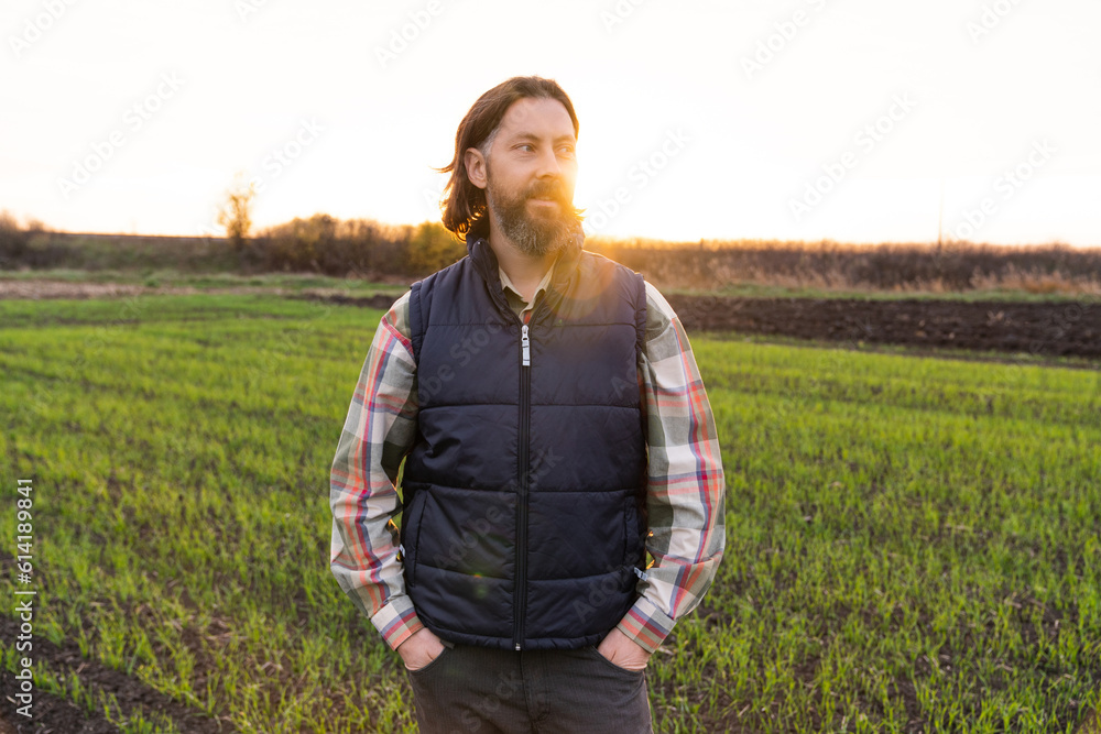 Portrait of bearded farmer on a field at sunset..