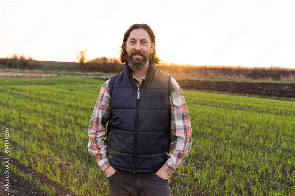 Portrait of bearded farmer on a field at sunset..