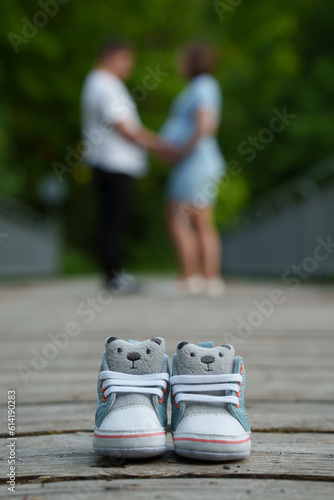 small baby sneakers, in the background the expectant parents / pregnant couple blurred