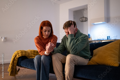 Obraz na plátne Young loving supportive woman wife holding hand of worried husband, showing support for partner during difficult times
