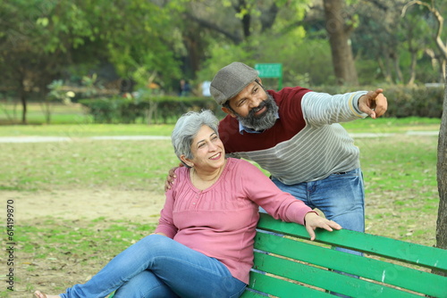 Young Indian Happy couple sitting on a park bench in a serene atmosphere taking a selfie