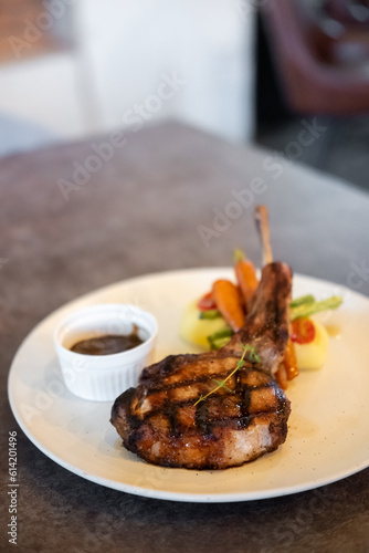 Grilled pork chop served on plate with sauce