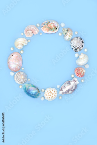 Seashell and oyster pearl wreath decoration. Summer garland with collection of assorted shells and pearls on blue background. Circular natural nature design, beach and seaside art.