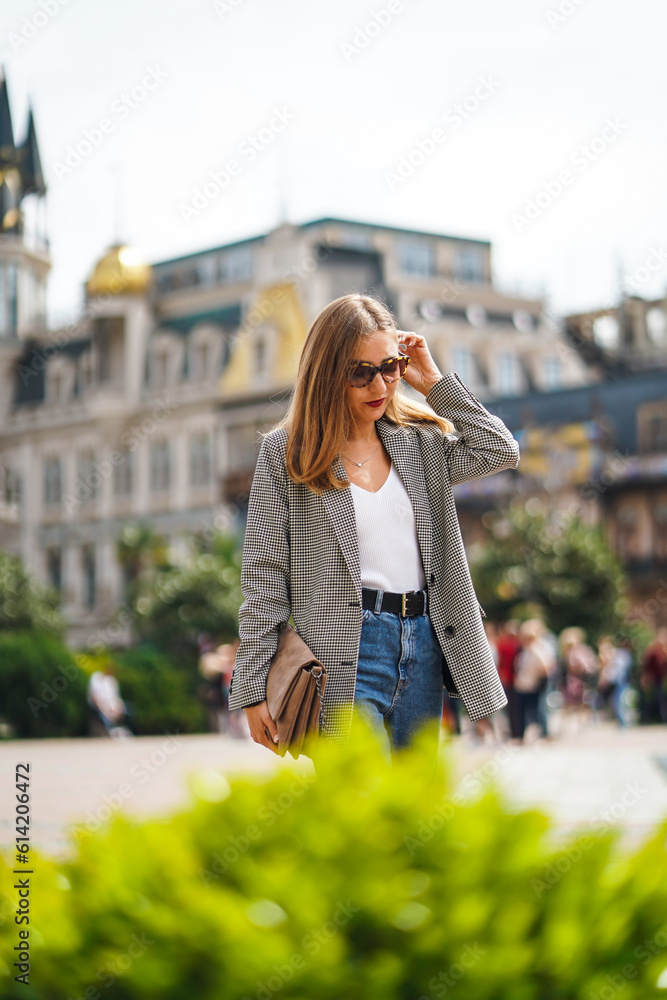 Girl walking through historic city area. Woman wearing sunglasses looks down. Girl walks around city against background of beautiful architectural buildings. Batumi City in Georgia Girl walking through historic city area. Woman wearing sunglasses looks down. Girl walks around city against background of beautiful architectural buildings. Batumi City in Georgia