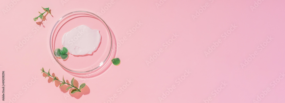 Petri dish with cream on a pink background. Surrounded by plants.