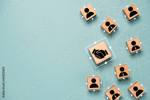 Murais de parede Top view design on blue background of Hand shaking which print screen on wooden cube block which connection with human icon for business deal and agreement concept