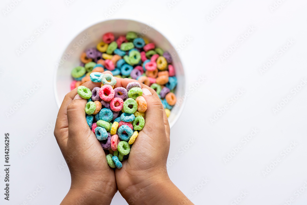 manos de niño empuñando cereal dulce de colores manos de niño empuñando cereal dulce de colores