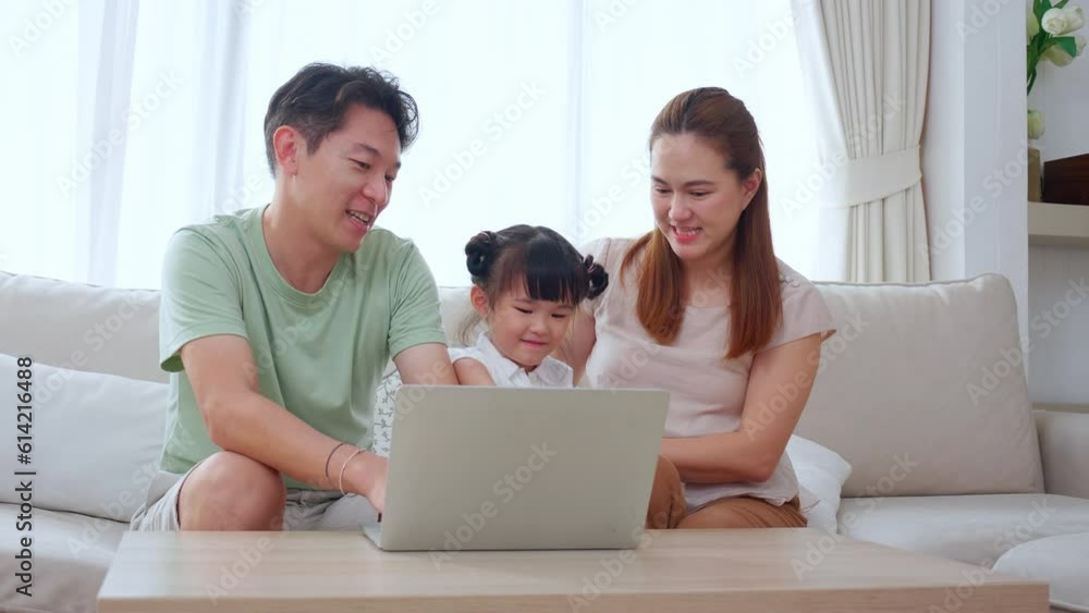 Happiness family dad and mom sitting and watching laptop computer for learning with daughter with enjoy on sofa in living room at home, father and mother looking notebook with kid for education. Happiness family dad and mom sitting and watching laptop computer for learning with daughter with enjoy on sofa in living room at home, father and mother looking notebook with kid for education.