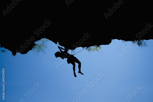 Fototapeta Naklejka Na Ścianę i Meble -  silhouette of climber hiking high on top of the rock mountain with rope,active sport adventure extreme exercise,concept for strong athlete