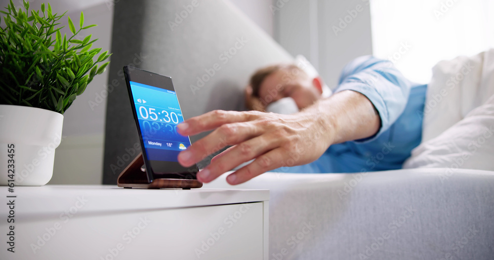 Man Waking Up With Alarm On Mobile Phone Man Waking Up With Alarm On Mobile Phone