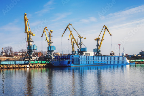 Sea port with cranes, barge and railway carriages.