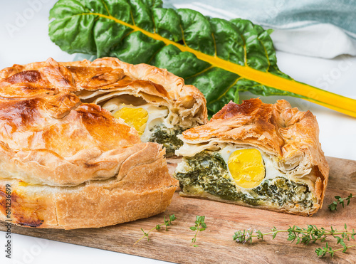 Torta pasqualina made with yellow chard. One slice is cut out and has the egg exposed.