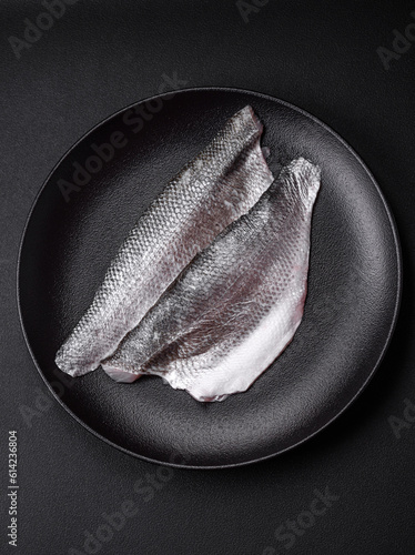 Raw sea bass fish fillet with salt, spices and herbs on a ceramic plate photo
