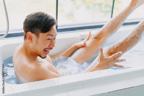 Funny asian man play and pose in a bathtub in the bathroom.