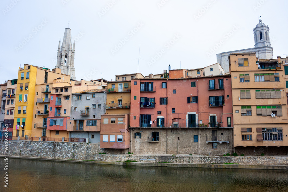 casas de colores de Girona en Cataluña vistas desde la orilla opuesta con el campanario de una iglesia de fondo y el cielo azul