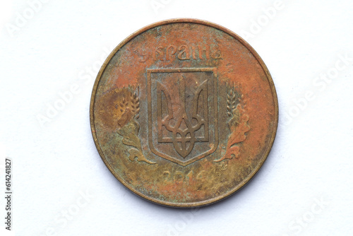 the reverse of a 2014 Ukrainian 25 kopeck coin that has been in circulation and has significant wear, rust and scratches, close-up on a white background