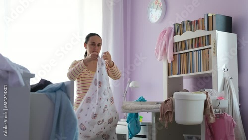 Mother tidying up changing table in messy nursery. Housekeeping and household concept