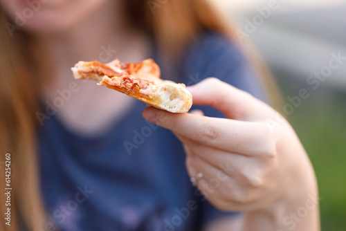 Woman eating tasty pizza outdoor in street cafe. Fast food takeaway in sunny day