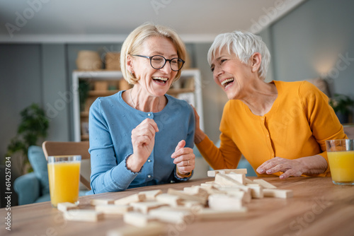 two senior women friends or sisters play leisure board game at home