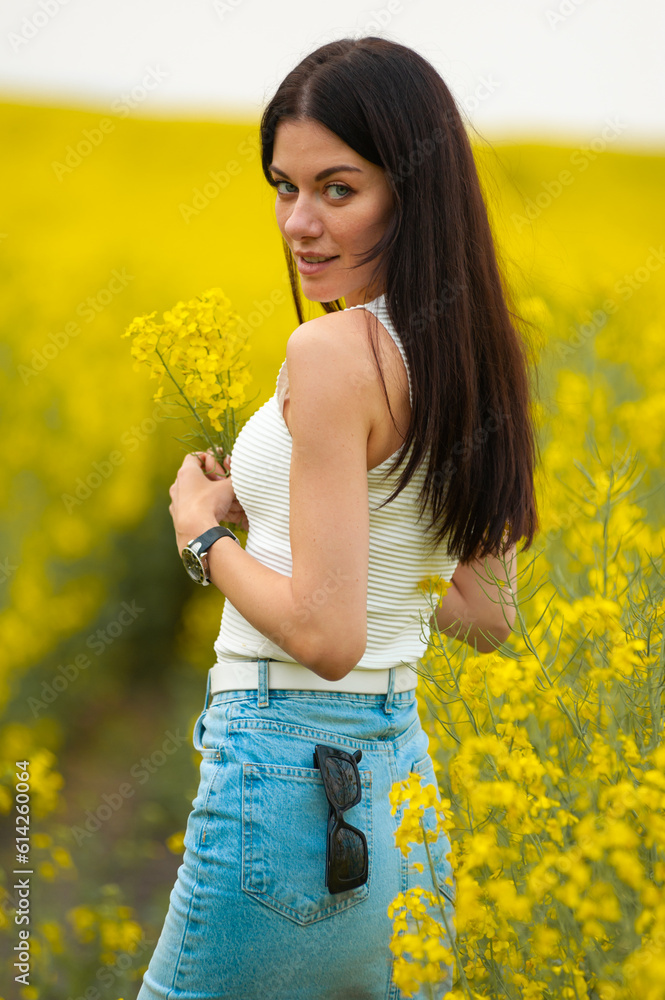 Happy beautiful woman walking on the field with yellow flowers