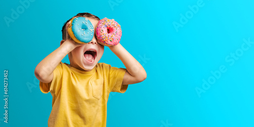 Happy cute boy is having fun played with donuts Bright photo of a child.