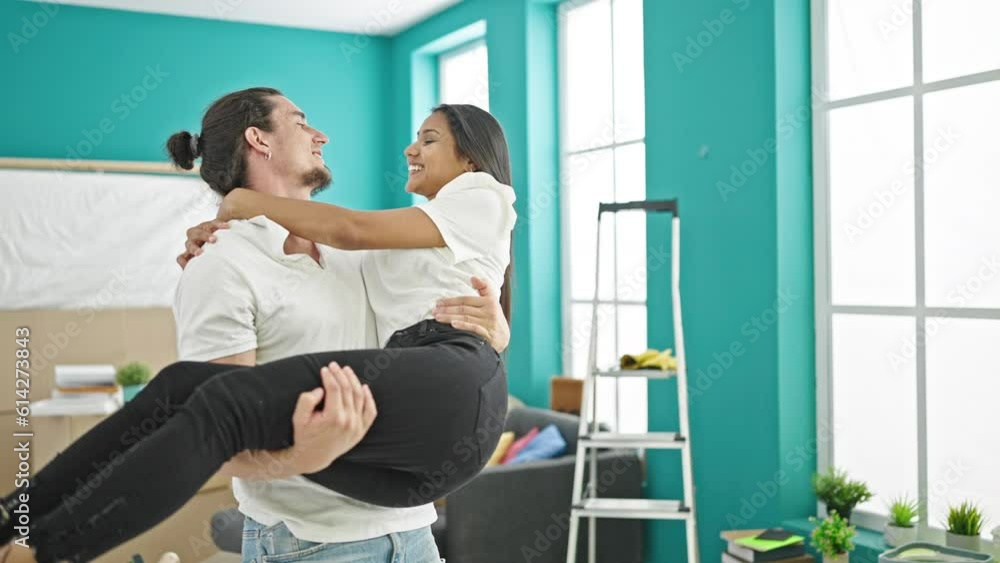 Man and woman couple holding girlfriend on air turning by himself at new home Man and woman couple holding girlfriend on air turning by himself at new home