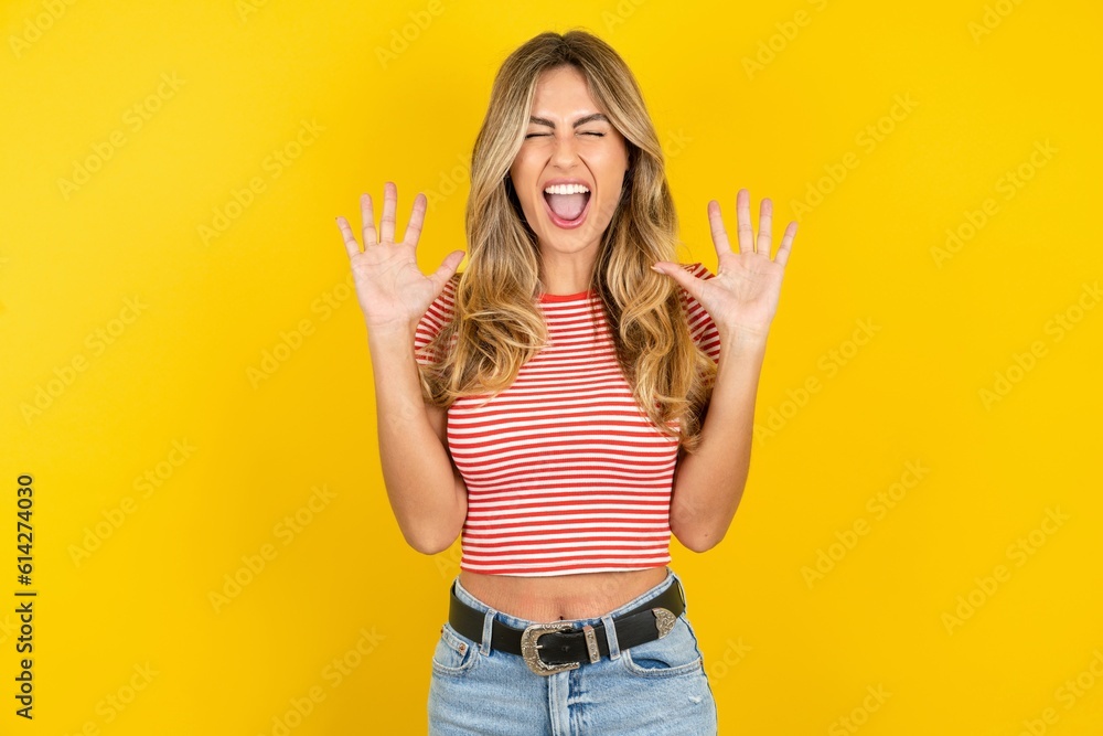 Emotive Young beautiful woman wearing striped t-shirt over yellow background laughs loudly, hears funny joke or story, raises palms with satisfaction, Emotive Young beautiful woman wearing striped t-shirt over yellow background laughs loudly, hears funny joke or story, raises palms with satisfaction,