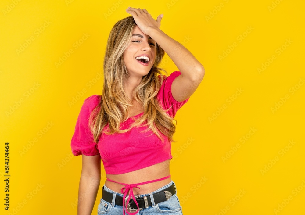 Young beautiful blonde woman wearing pink crop top over yellow studio background surprised with hand on head for mistake, remember error. Forgot, bad memory concept. Young beautiful blonde woman wearing pink crop top over yellow studio background surprised with hand on head for mistake, remember error. Forgot, bad memory concept.