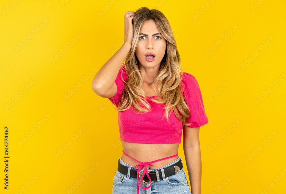 Embarrassed Young beautiful blonde woman wearing pink crop top over yellow studio background with shocked expression, expresses great amazement, Puzzled model poses indoor Embarrassed Young beautiful blonde woman wearing pink crop top over yellow studio background with shocked expression, expresses great amazement, Puzzled model poses indoor