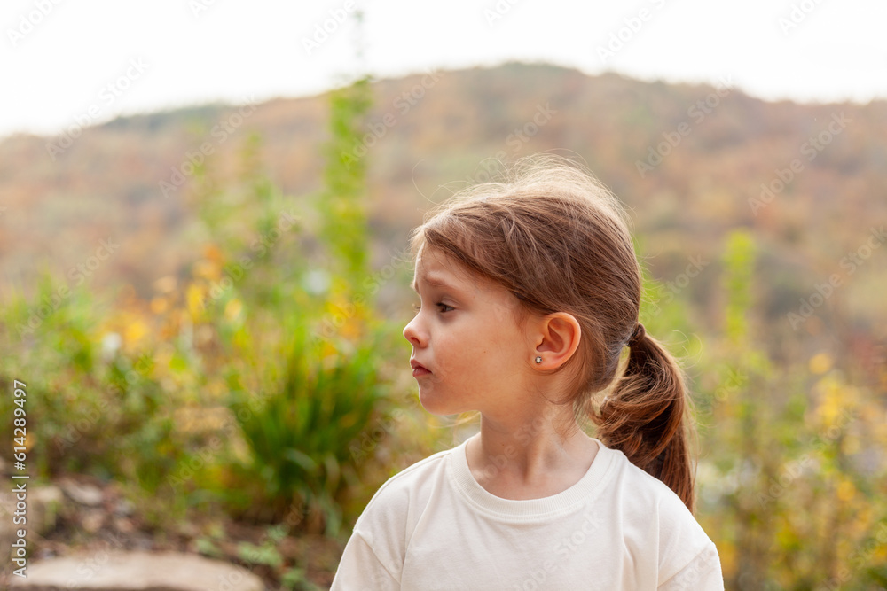 Portrait of a little girl in a white T-shirt on nature background