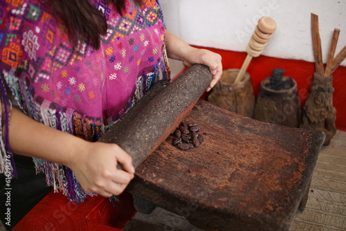 Guatemalan mayan woman making chocolate with traditional grinding stone