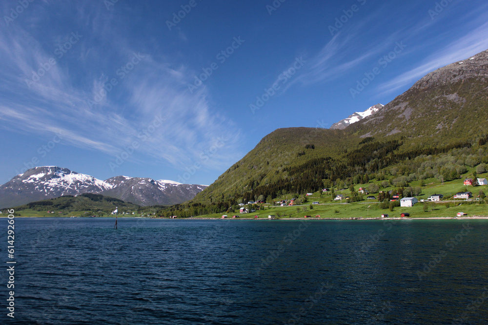 Fjord, houses near the sea in Northern Norway, sea, wooded mountains, snowy mountains