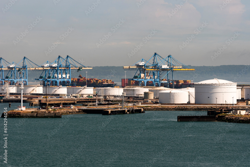 Le Havre, northern France, Europe. 2023. Cranes in the container port and storage  tanks alongside a jetty in the Port of Le Havre, France.