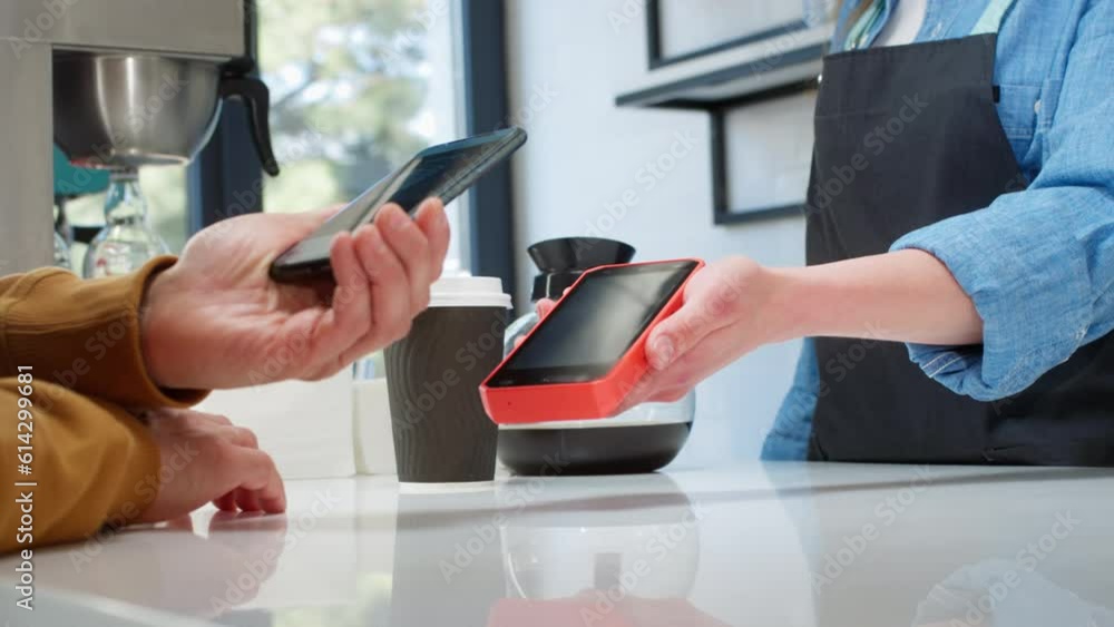 Close-up: a customer makes a purchase in a coffee shop, pays with a QR ...