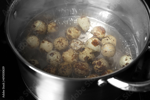 Cooking quail eggs in pot on electric stove, closeup