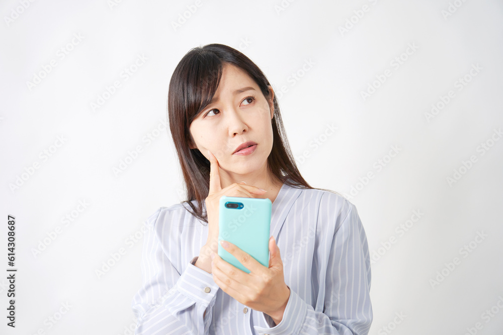 スマートフォンを持って悩むミドルエイジ女性 白背景 スマートフォンを持って悩むミドルエイジ女性 白背景