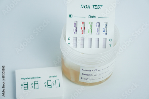 Examination of narcotic content in urine by placing the urine in a urine container and then immersing a portion of the drug test kit in the urine. isolated on white photo