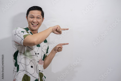 Young asian man wearing vintage shirt gesturing something, pointing, showing photo